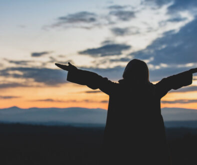 Sunset girl with arms outstretched in worship.